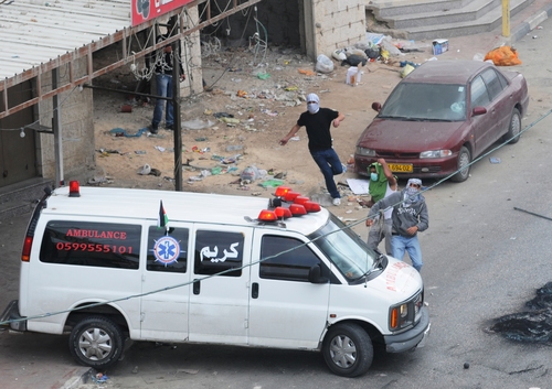 Click photo to download. Caption:Â Palestinians in Qalandiya use an ambulance for cover as they hurl rocks during a violent riot in May 2011. Credit: Israel Defense Forces.