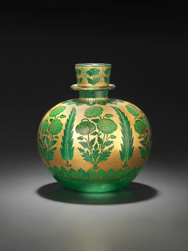 Huqqa (water pipe) of emerald-green glass decorated with gold and yellow enamel Northern India; 1st half of 18th century. The motif was painted “in reserve,” which means that the gold was largely used as the background for the motifs – poppies and cypresses along with various leaf borders. A few details, such as the ribs or little leaves, were executed in gold or yellow enamel. A special refinement is the use of enamel inside, behind the flower heads. Photo: The David Collection