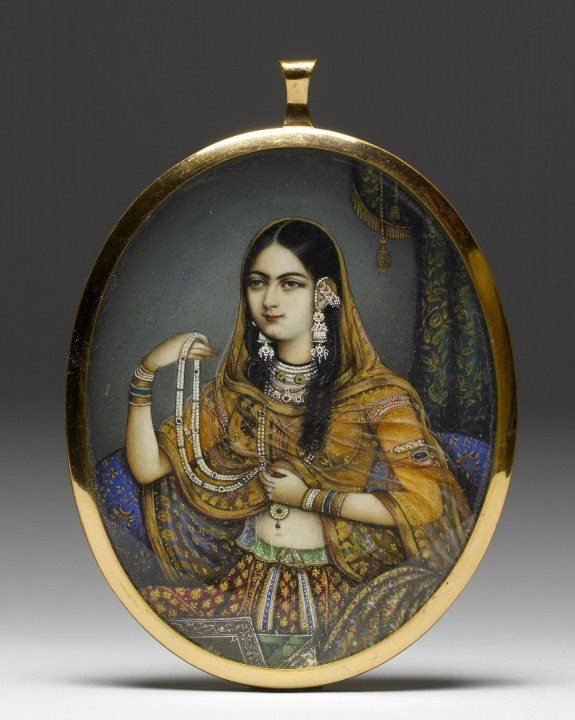 Miniature portrait pendant. Watercolor on ivory, gold, glass. 1830-1850, India. In this instance, an artist from Delhi has portrayed a courtesan dressed as a princess wearing elaborate Mughal gold and gem-set jewelry. Photo: The Walters Art Museum