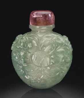 A rare Mughal pale green jadeite snuff bottle. 1800-1900. The flattened, rounded bottle is well carved on either side with a large flower reserved on a dense ground of overlapping leaves. Either shoulder is carved with a smaller flower head as is the top of the mouth rim. The translucent stone is of pale icy green tone. 2 in. (5 cm.) high, pink tourmaline stopper and bone spoon.