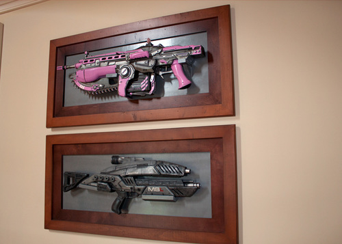TOP: Lauren's 1 of a kind pink lancer made by Triforce and given to her by Clifford for her birthday at Comic Con. BOTTOM: Lauren's M-8 avenger assault rifle from Mass Effect Series! (These are right outside the game room, in the hallway.)