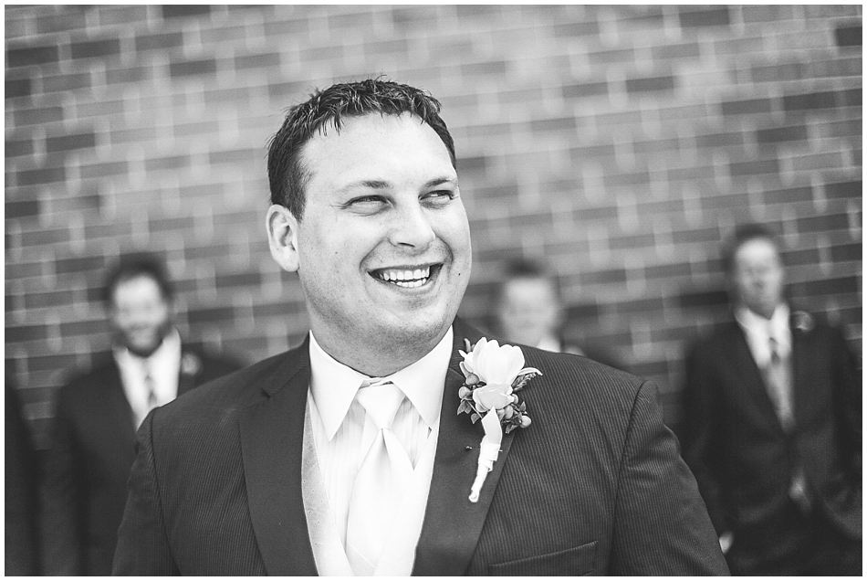 Groom laughing and looking off camera in black and white