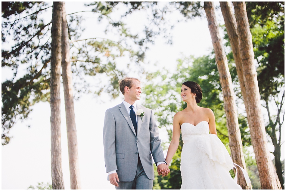 Bride and groom walking and looking at each other on golf course cart path