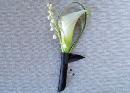 groomsmen boutonniere with a white mini calla, lily of the valley and variegated lily grass