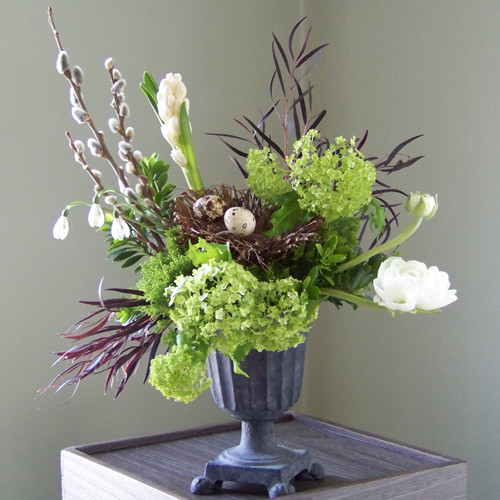 centerpiece, a nest of quail eggs is displayed in a small cast iron urn and is surrounded with French pussy willow, hyacinth, agonis, viburnum, ranunculus, euonymus foliage, jade trachelium and snow drops