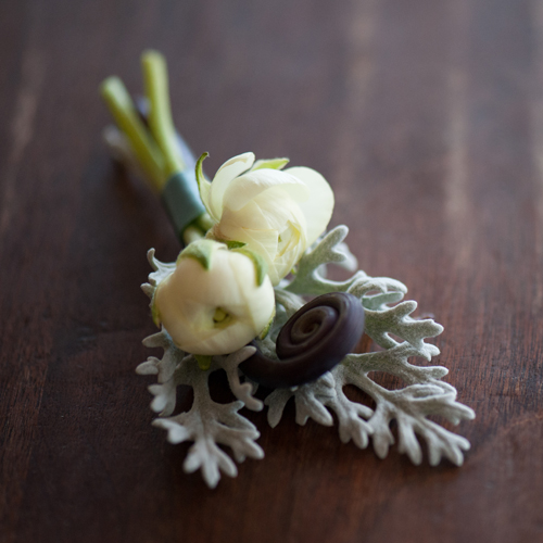 Boutonniere of ivory ranunculus accented with dusty miller and a uhule fern curl. Photo by The R2 Studio.