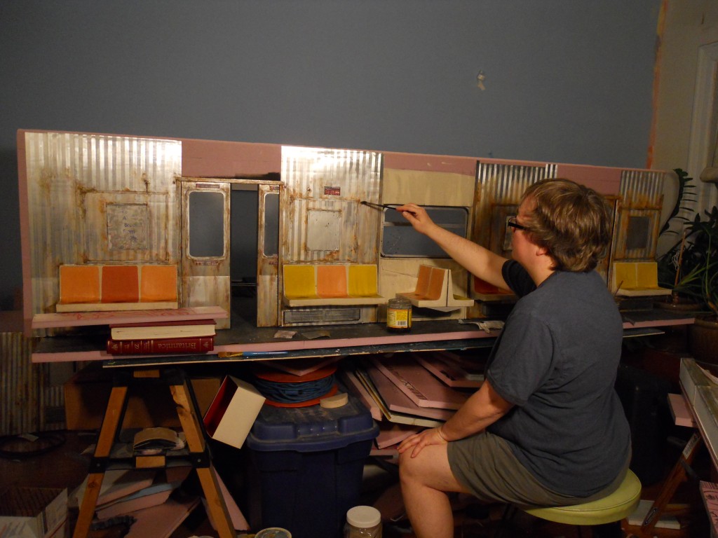 Subway seats attached to back wall of model. Lori fine tunes the dirty and rusty finish. 