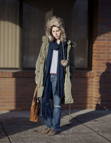 Jillian, an RIT Rochester Institute of Technology student, wears a tan fur lined parka over a white shirt and jeans with a large blue scarf.
